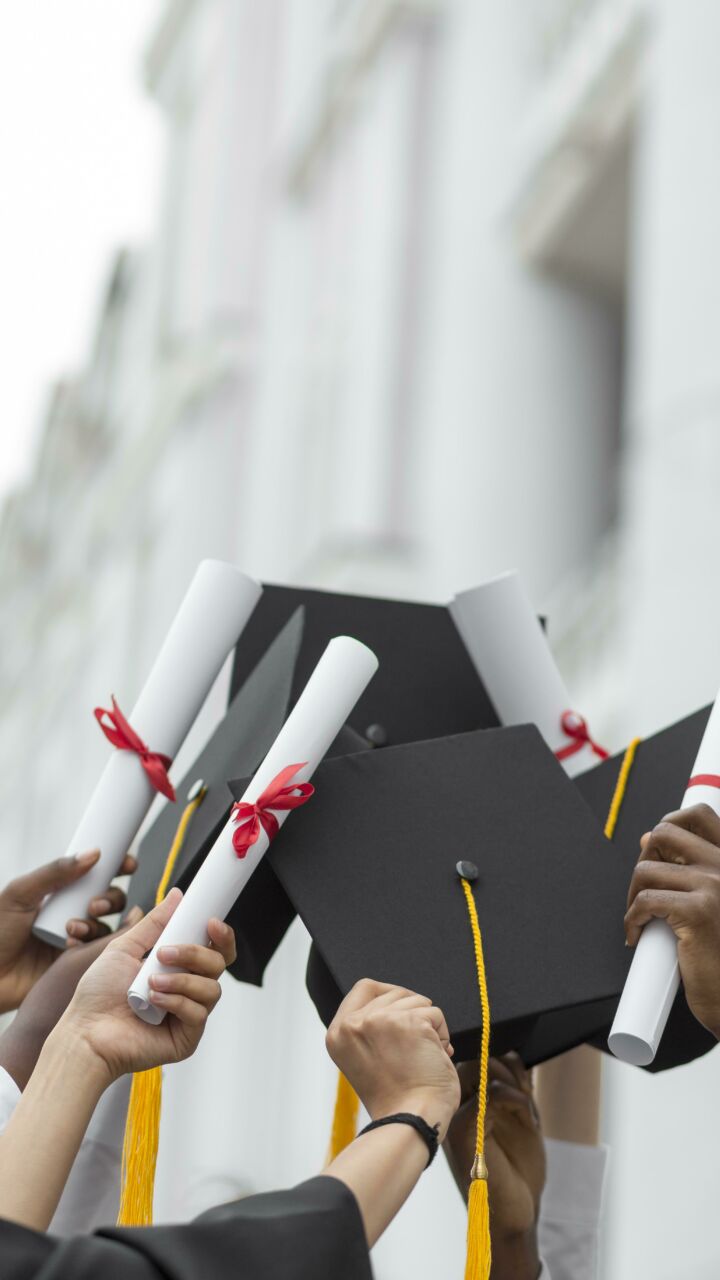 Close up hands holding diplomas caps